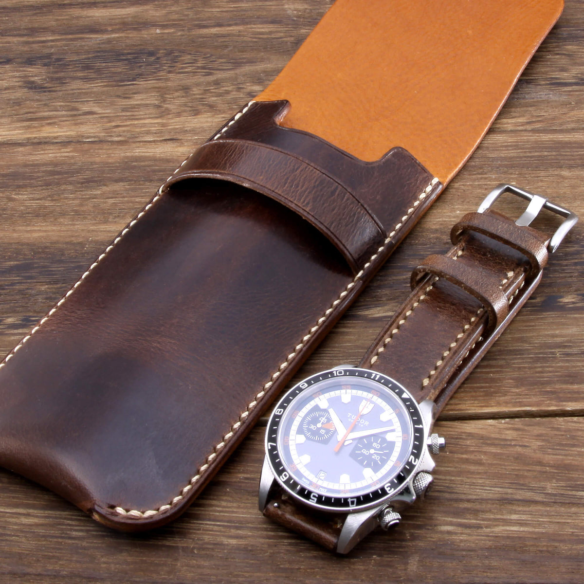 Lined leather watch pouch built for travel hand crafted by Cozy Handmade, displayed on a wooden desk next to a luxury watch.