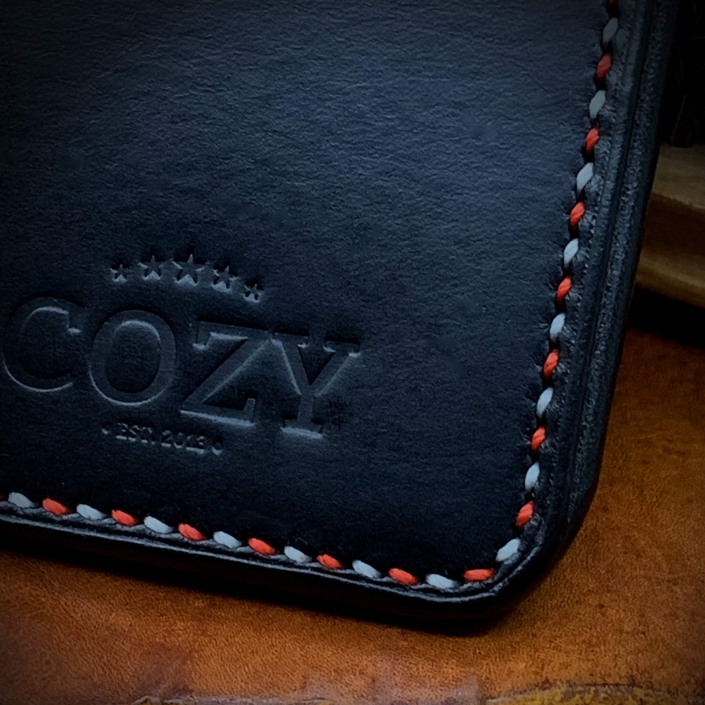 Close-up of COZY stamp on Slim Sleeve Wallet SG Edition in pure black full grain leather with red and white alternating saddle stitch detail