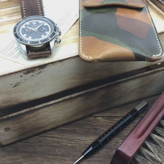 Video demonstrating a handcrafted camouflage leather watch pouch by Cozy Handmade, showing the secure strap closure and its compact size for safe travel.