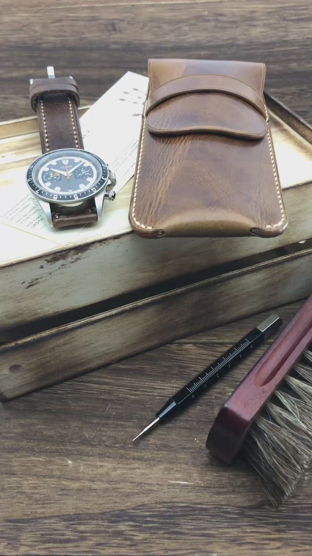 Hands-on showcase of a dark brown leather watch sleeve by Cozy Handmade, demonstrating the secure strap closure and thick protective lining.