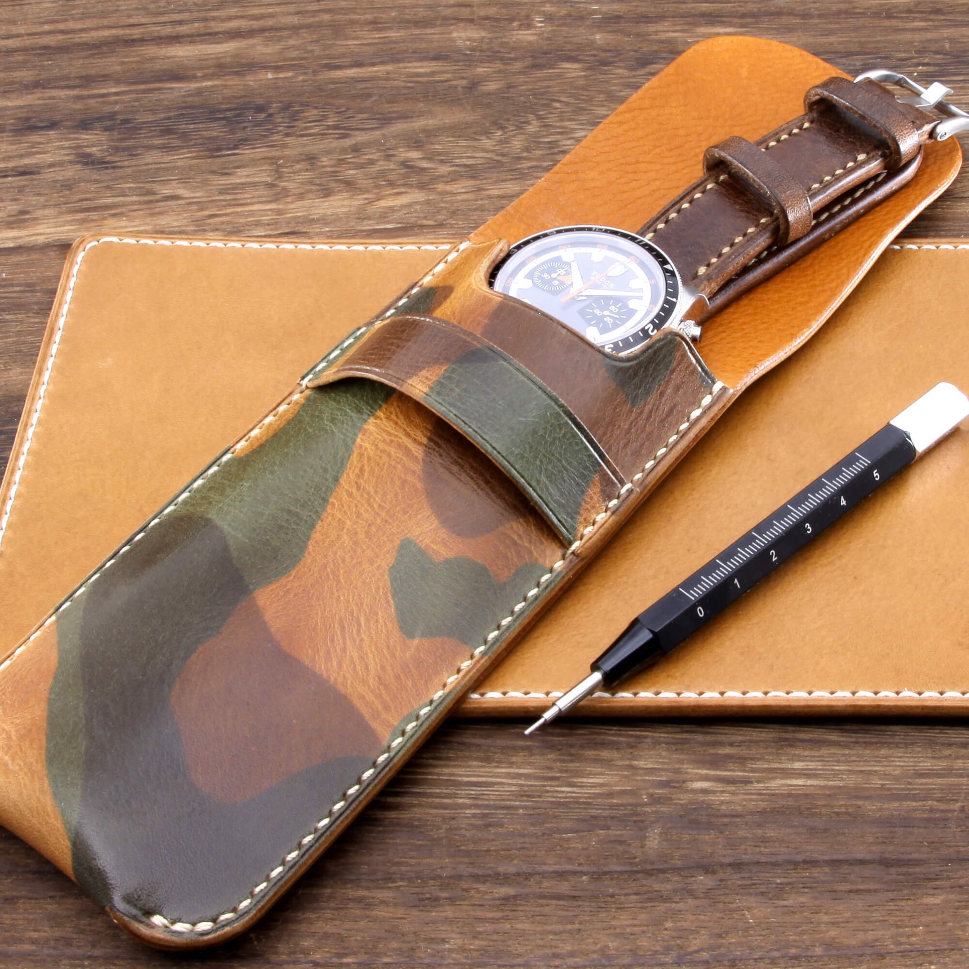 Premium Italian vegetable-tanned leather watch slip case in Military 101 featuring grey contrast stitching, resting on a leather valet and wooden desk. Hand crafted by Cozy Handmade