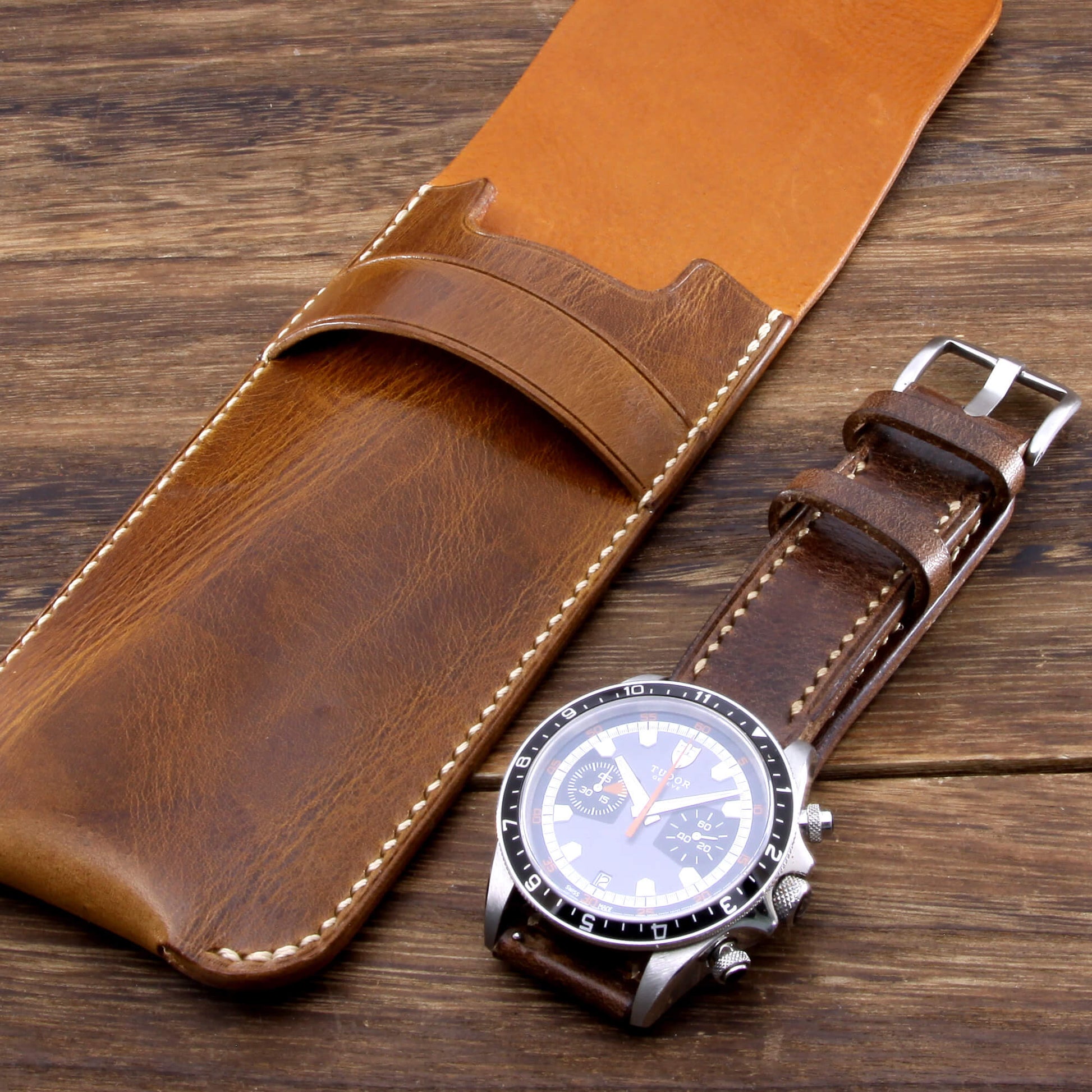 Premium Italian vegetable-tanned leather watch slip case in military 102, placed on a wooden desk beside a luxury timepiece.