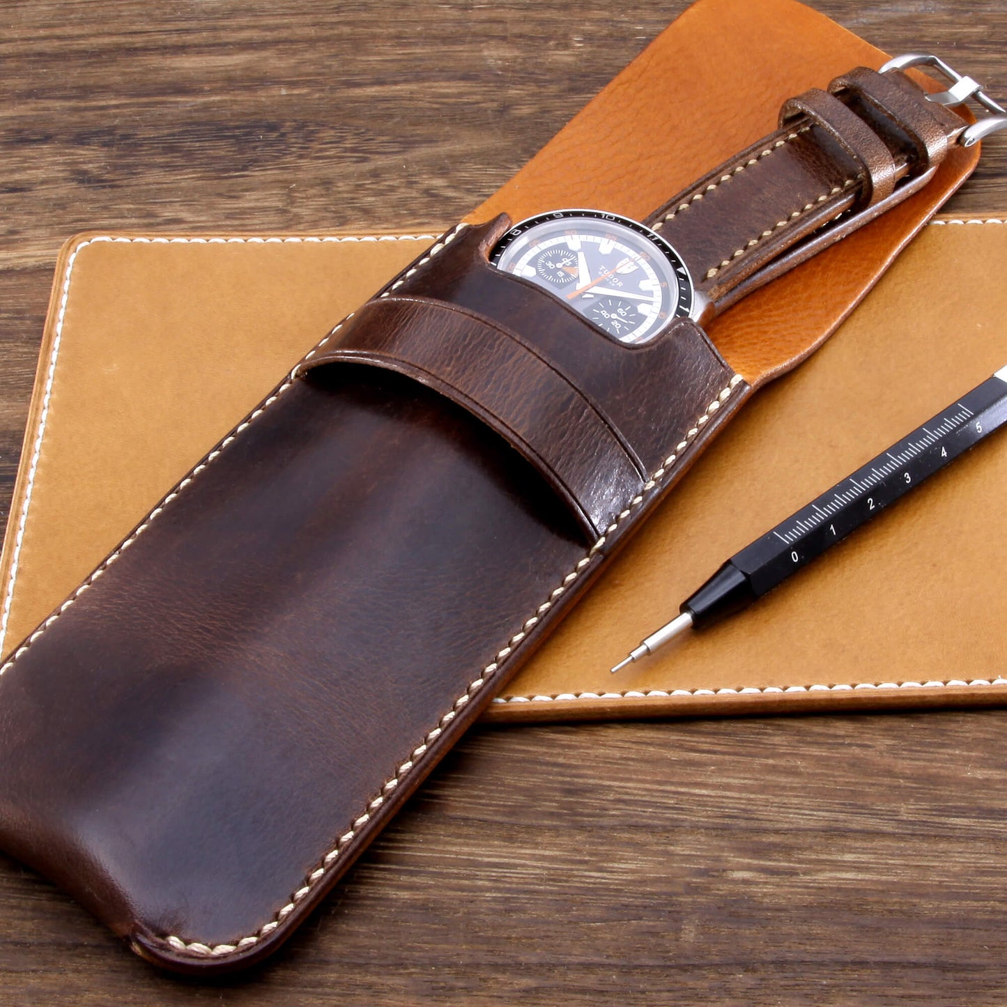 Premium Italian vegetable-tanned leather watch slip case in Military 103 featuring grey contrast stitching, resting on a leather valet and wooden desk. Hand crafted by Cozy Handmade